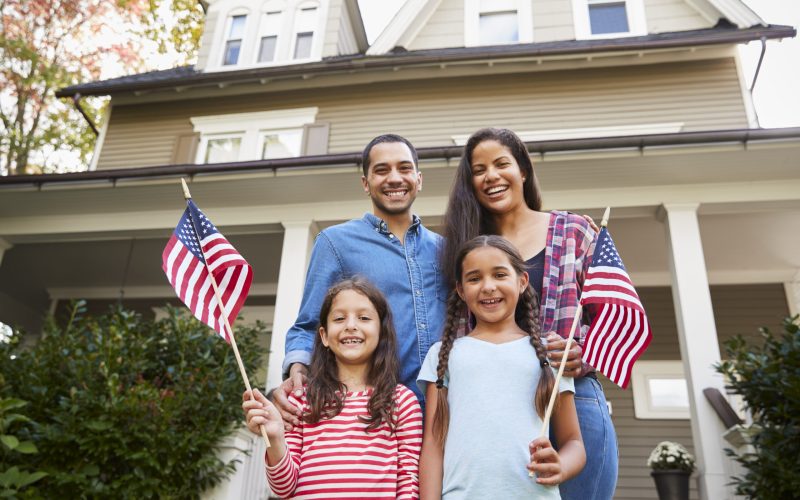 Portrait Of Family Outside House Holding American Flags