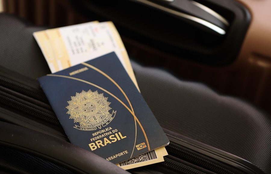 Federative Republic of Brazil passport with tickets lies on touristic suitcase close up in airport waiting hall. Travel worldwide and international tourism concept S